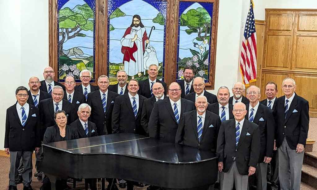 Group of men in front of a stained glass window of the Good Shepherd