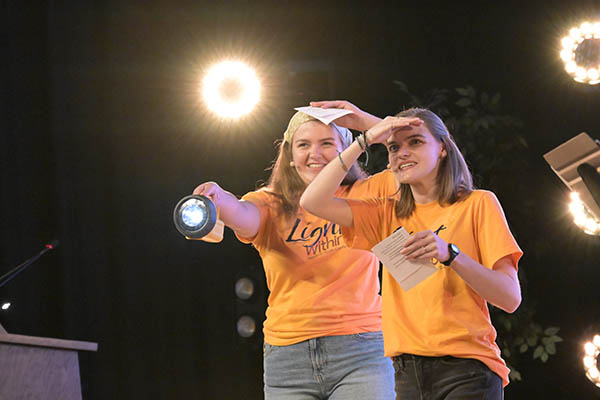 Two people holding a large flashlight and looking for something