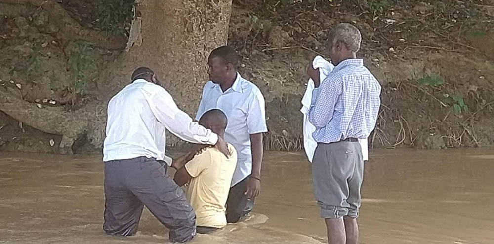 Men in river baptizing a person
