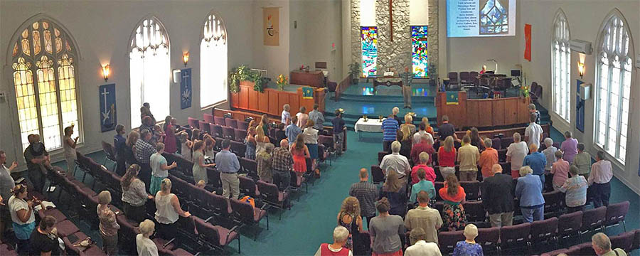 People standing in a church building with colorful glass
