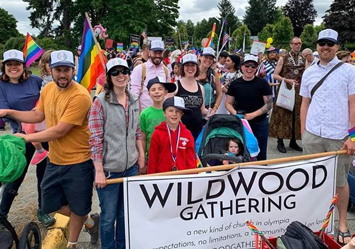 Smiling people behind a sign for Wildwood Gathering