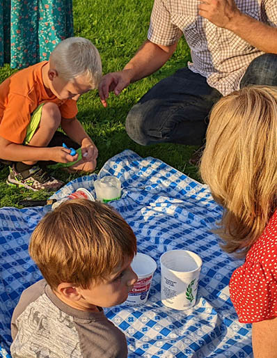 Children with ice around tablecloth on the grass