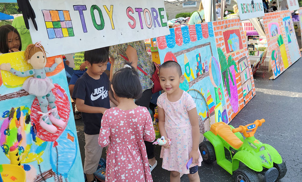 Children in front of a handmade sign that says "Toy store"