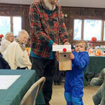 Grandfather and grandchild with a birdhouse made to look like Rudolph
