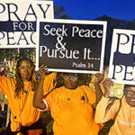 People holding signs saying "Pray for Peace"