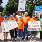 People in orange t-shirts carry anti-war signs