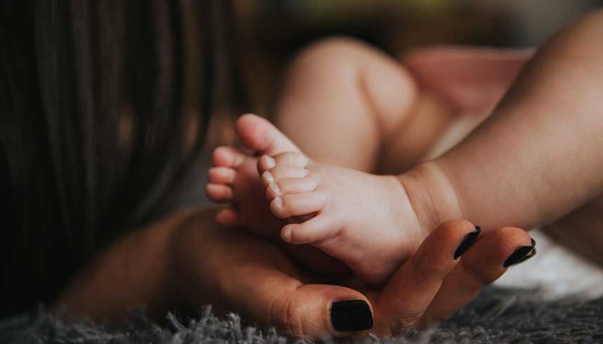 Adult hand holding baby feet