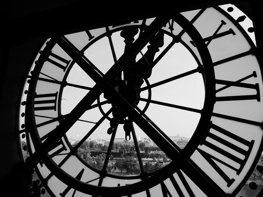 Black and white photo of city view through large clock