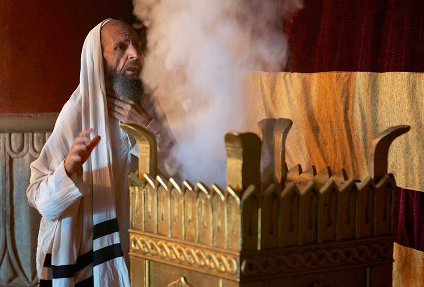 Older man with smoke rising from an altar.