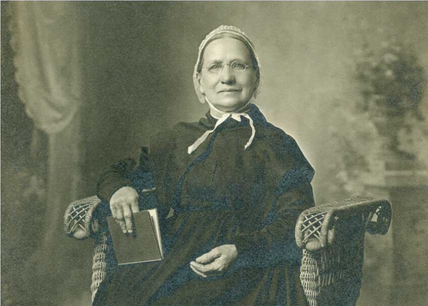 Julia Gilbert wearing a white head covering and holding a book