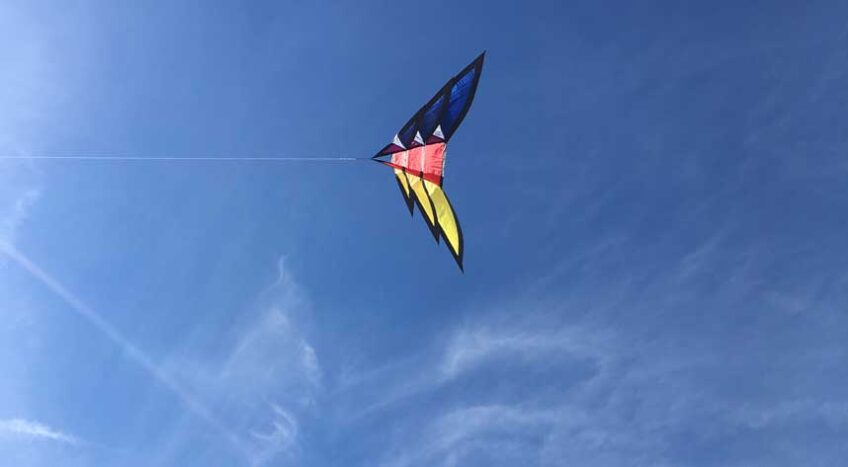 Colorful kite against blue sky with wispy clouds