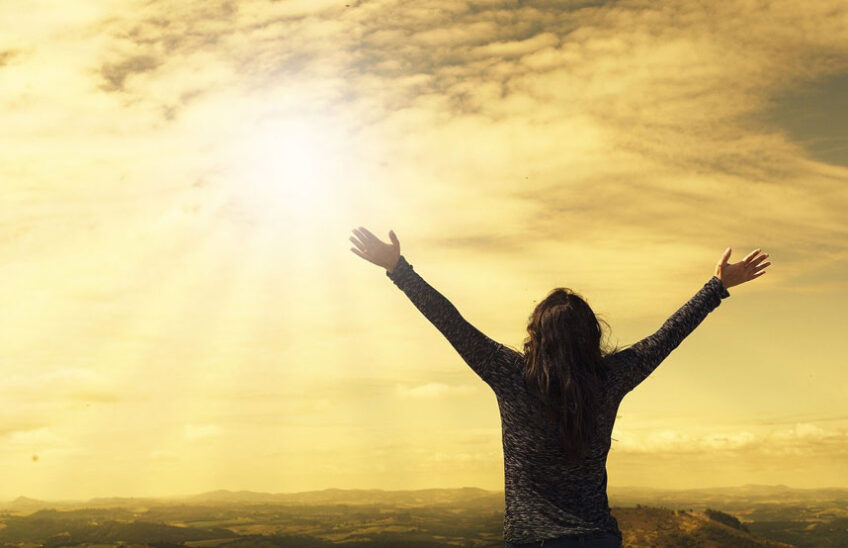 Woman with hands up facing sun