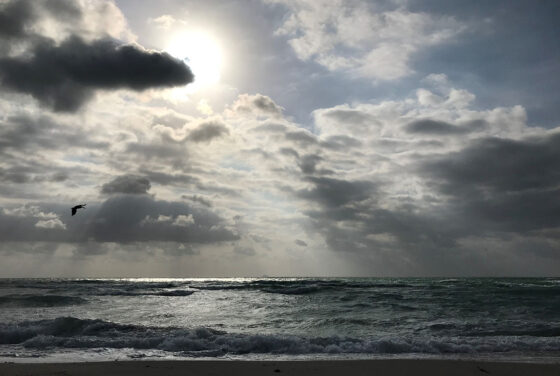Sun shining through dark clouds on the ocean