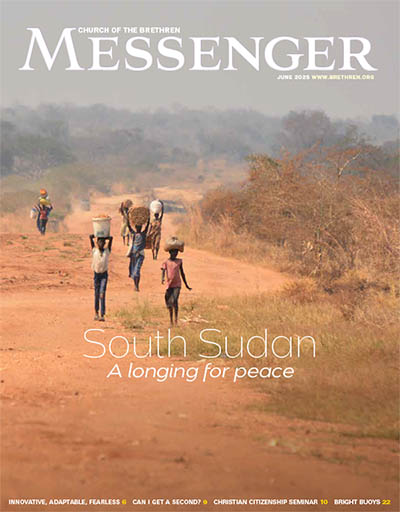 People walking on a dusty road in South Sudan carrying things on their heads