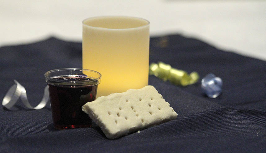 Candle, communion bread, and glass of grape juice