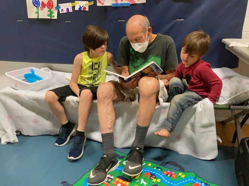 Man reading book to two children.