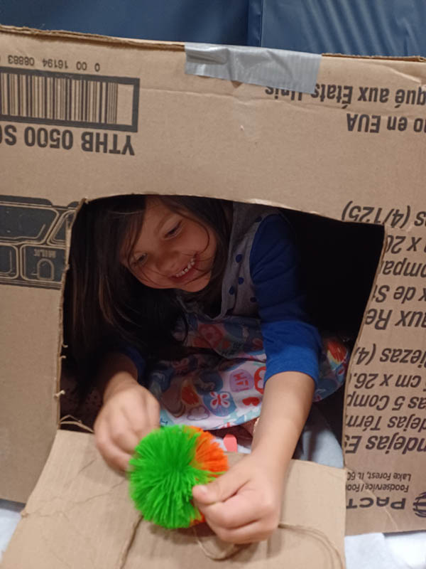 Girl in box plays with toy.