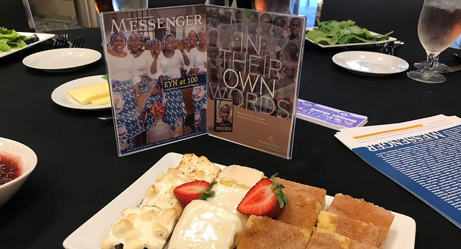 Table with plate of desserts and centerpiece highlighting Messenger and Brethren Press books
