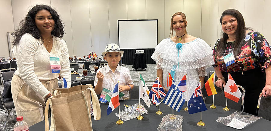 Three women and a child behind a table with flags from different countries.