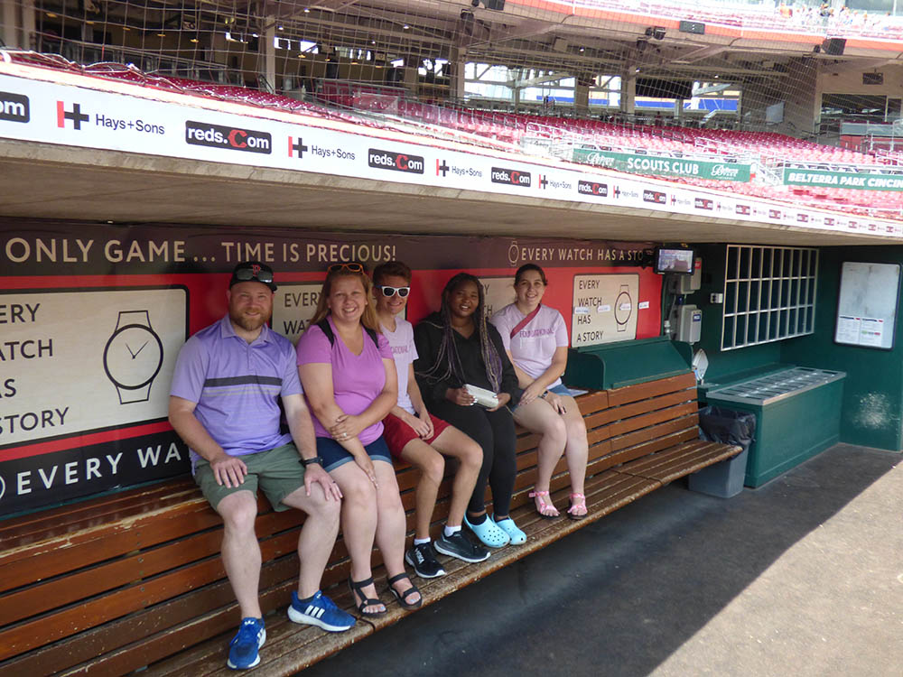 Five young adults sitting in a bench in the dugout