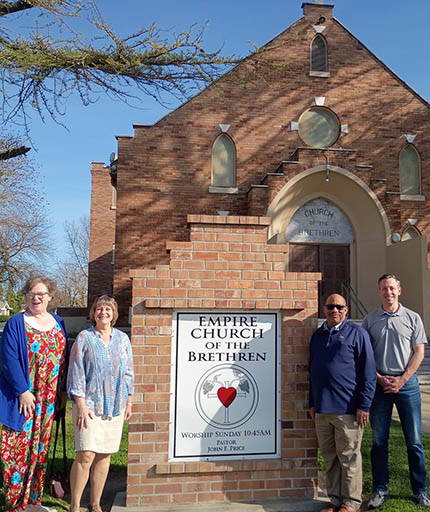 People standing by a sign that says Empire Church of the Brethren.