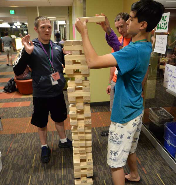 Teens stacking wooden blocks into a tall tower