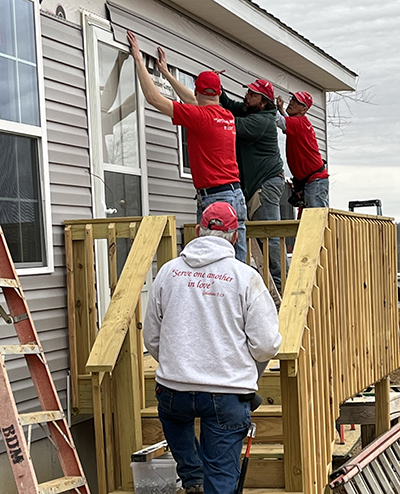 BDM volunteers replace siding on a house