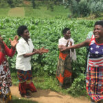 Batwa women dancing and clapping in a potato field
