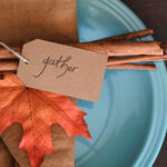 Cinnamon sticks, autumn leaf and tag saying "gather" on a plate