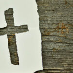 Paper torn into the shape of a cross nailed to wood