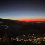 Sunset behind an airplane wing, with lights below