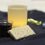 Candle, communion bread, and glass of grape juice